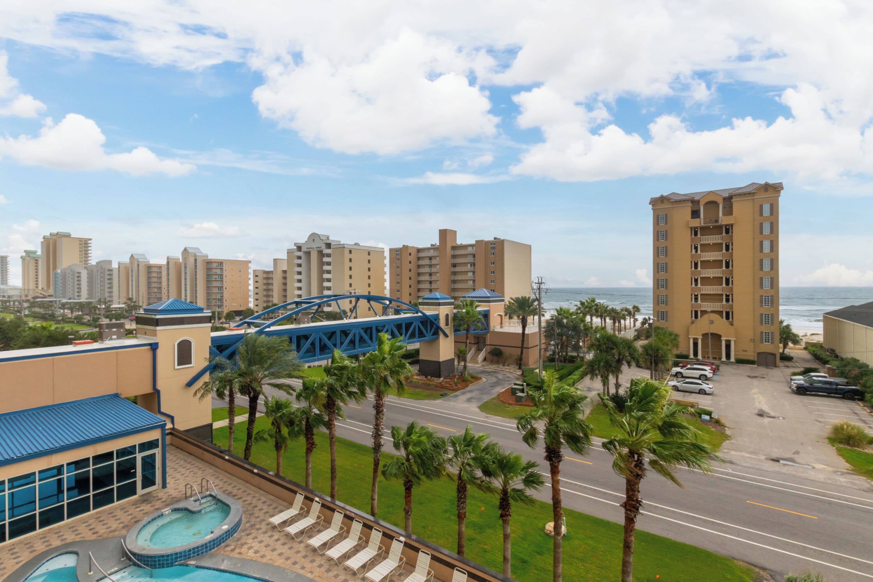 A hotel with a pool area, a bridge, and a view of the ocean.