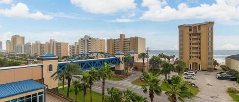 A hotel with a pool area, a bridge, and a view of the ocean.