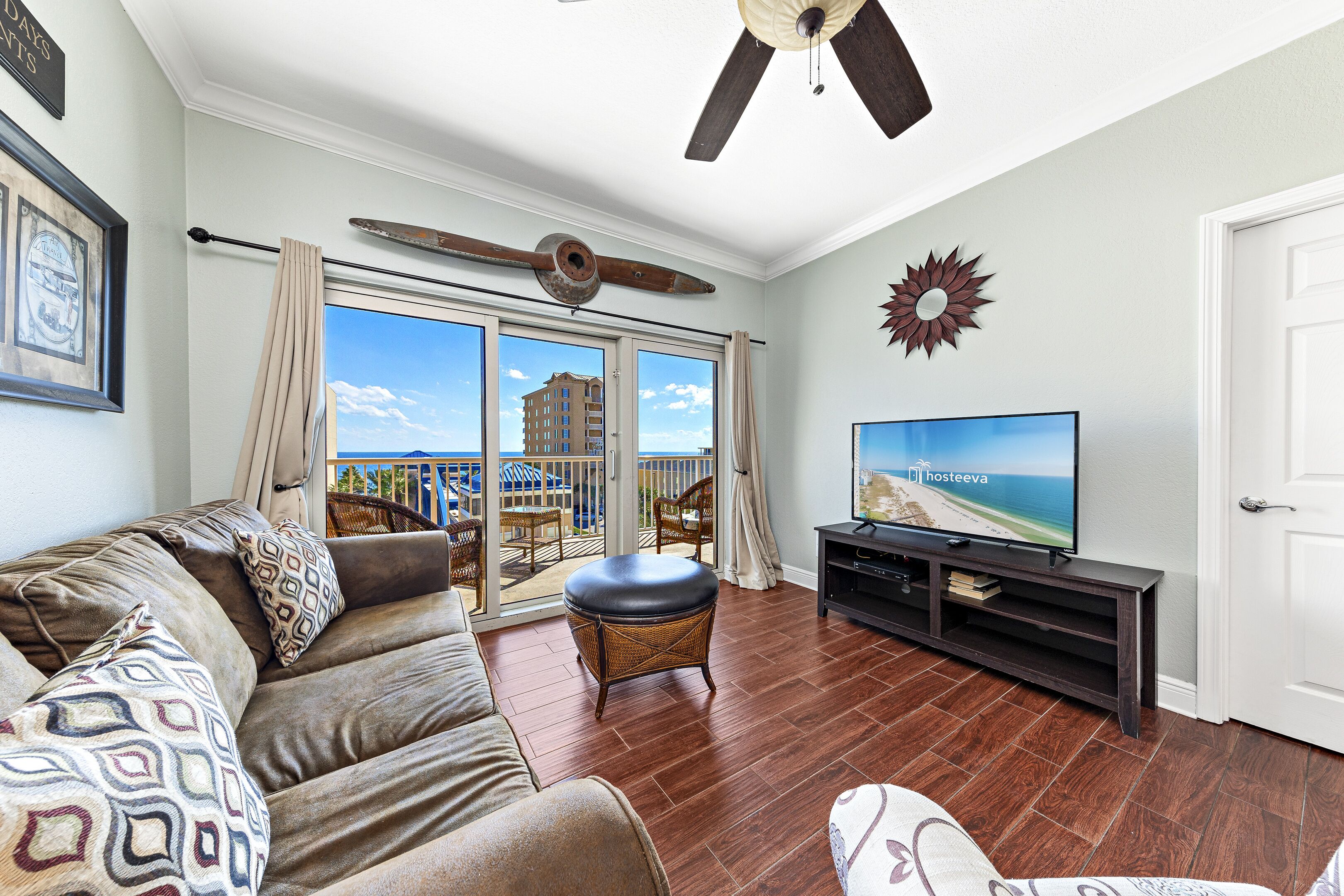 A living room with a sofa, ottoman, and entertainment unit with a TV.