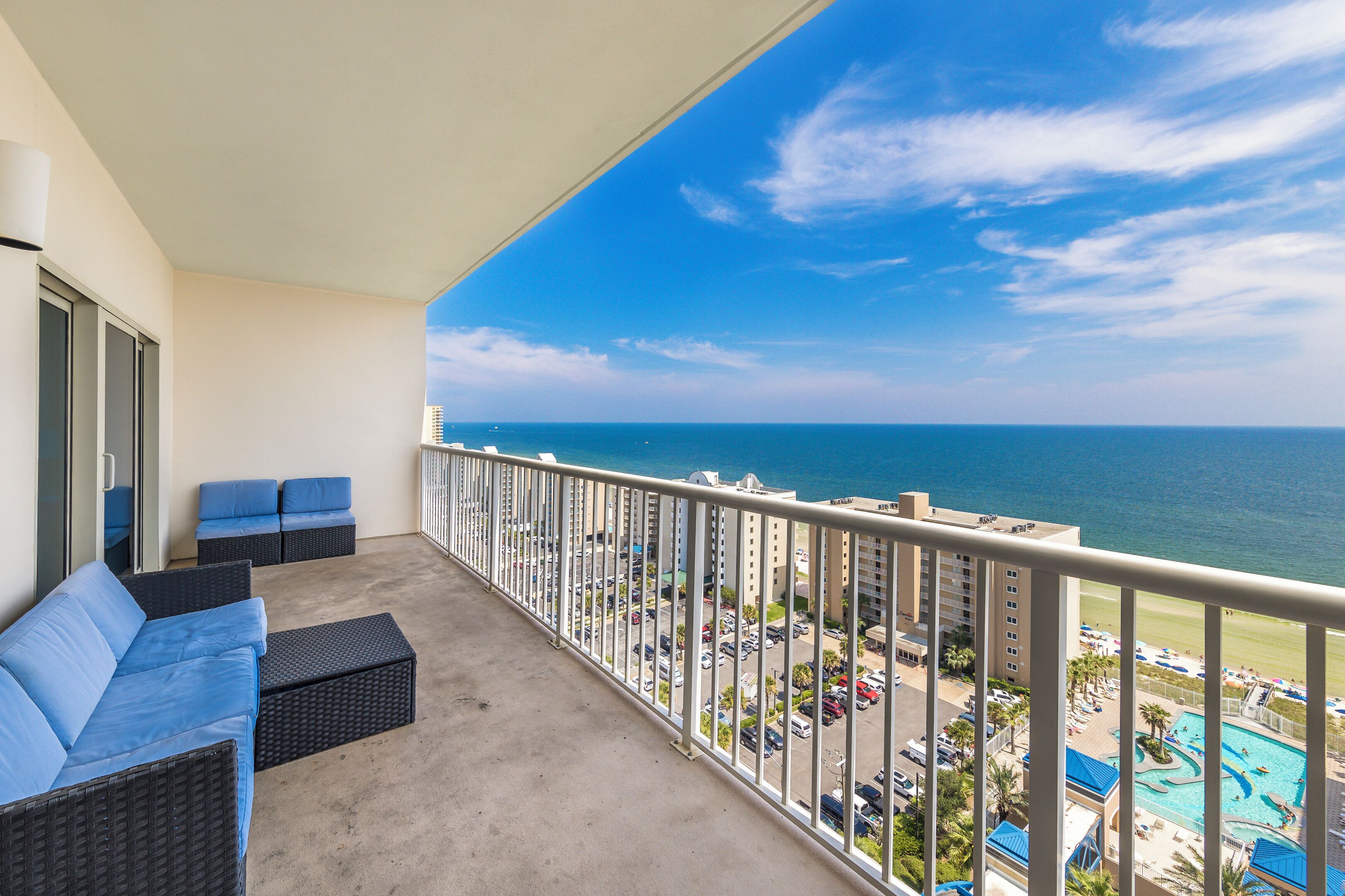 A balcony with a view of the ocean and a swimming pool.