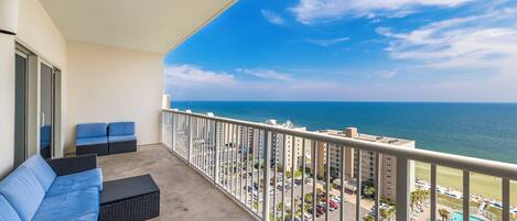A balcony with a view of the ocean and a swimming pool.