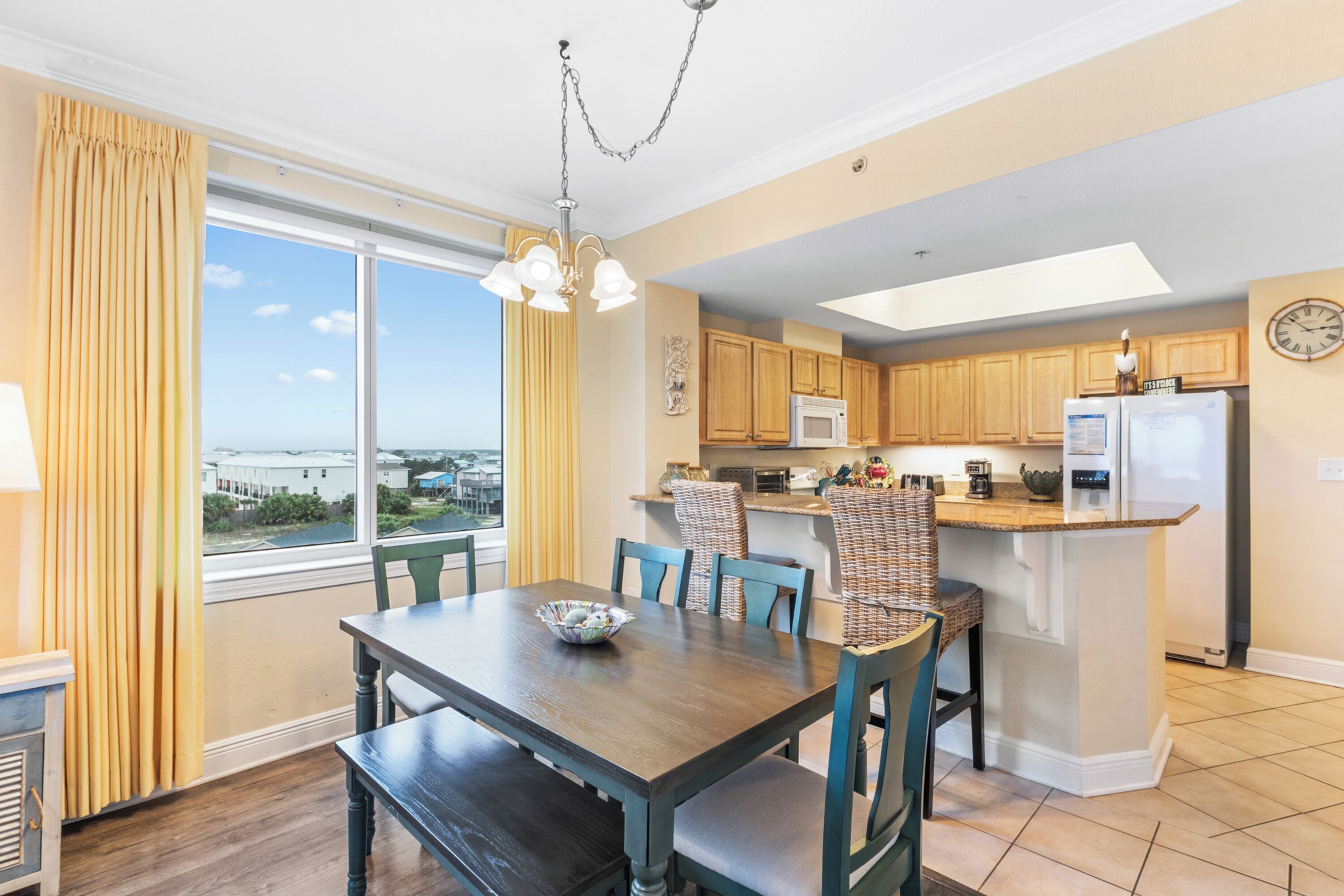 A modern kitchen with wooden cabinets, a central island, and a dining area with a table and chairs.