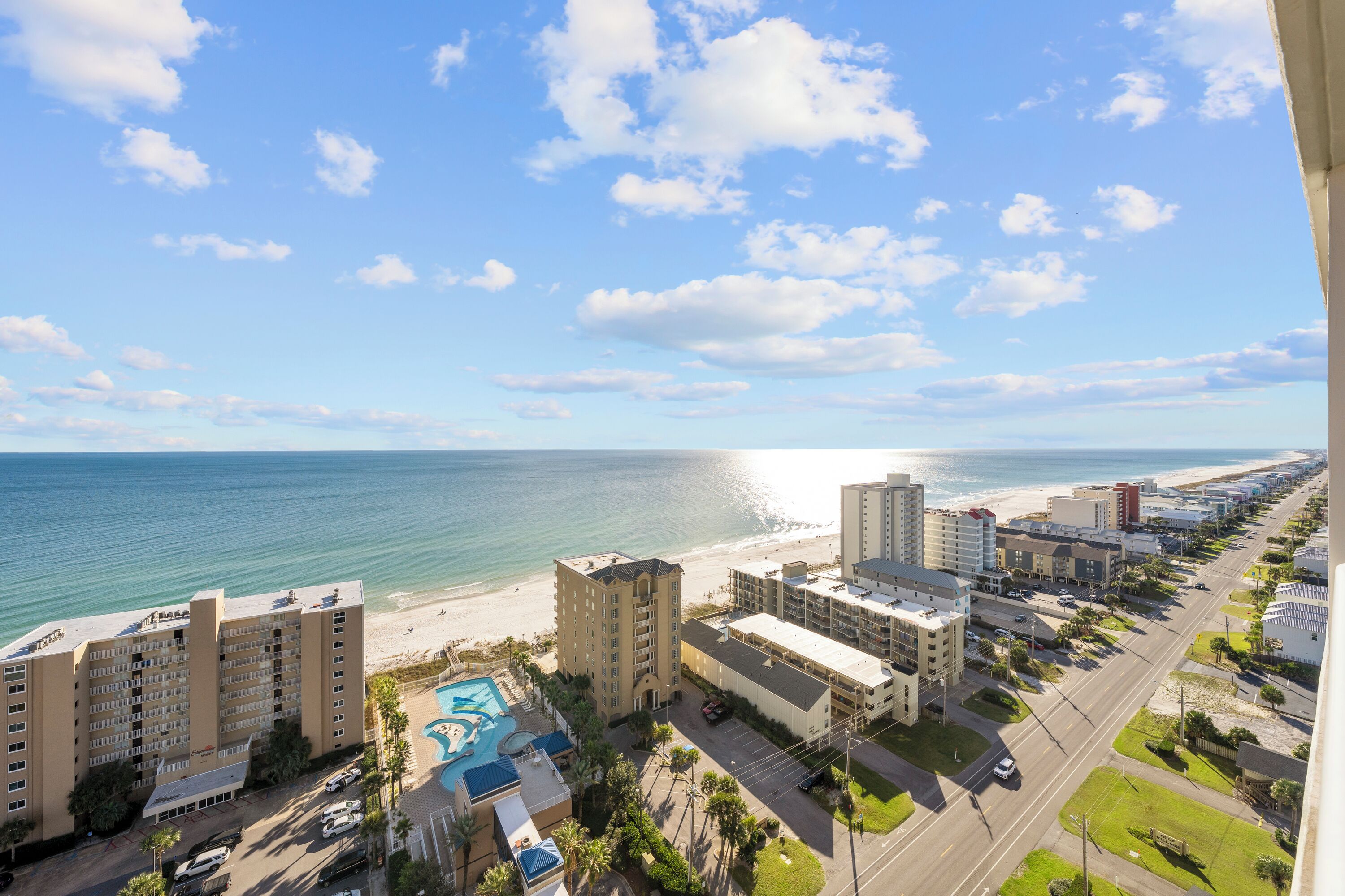 A coastal hotel with multiple buildings, a swimming pool, and a beach view.