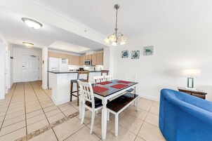A modern kitchen with white cabinets, a central island, and a dining area with a table and chairs.