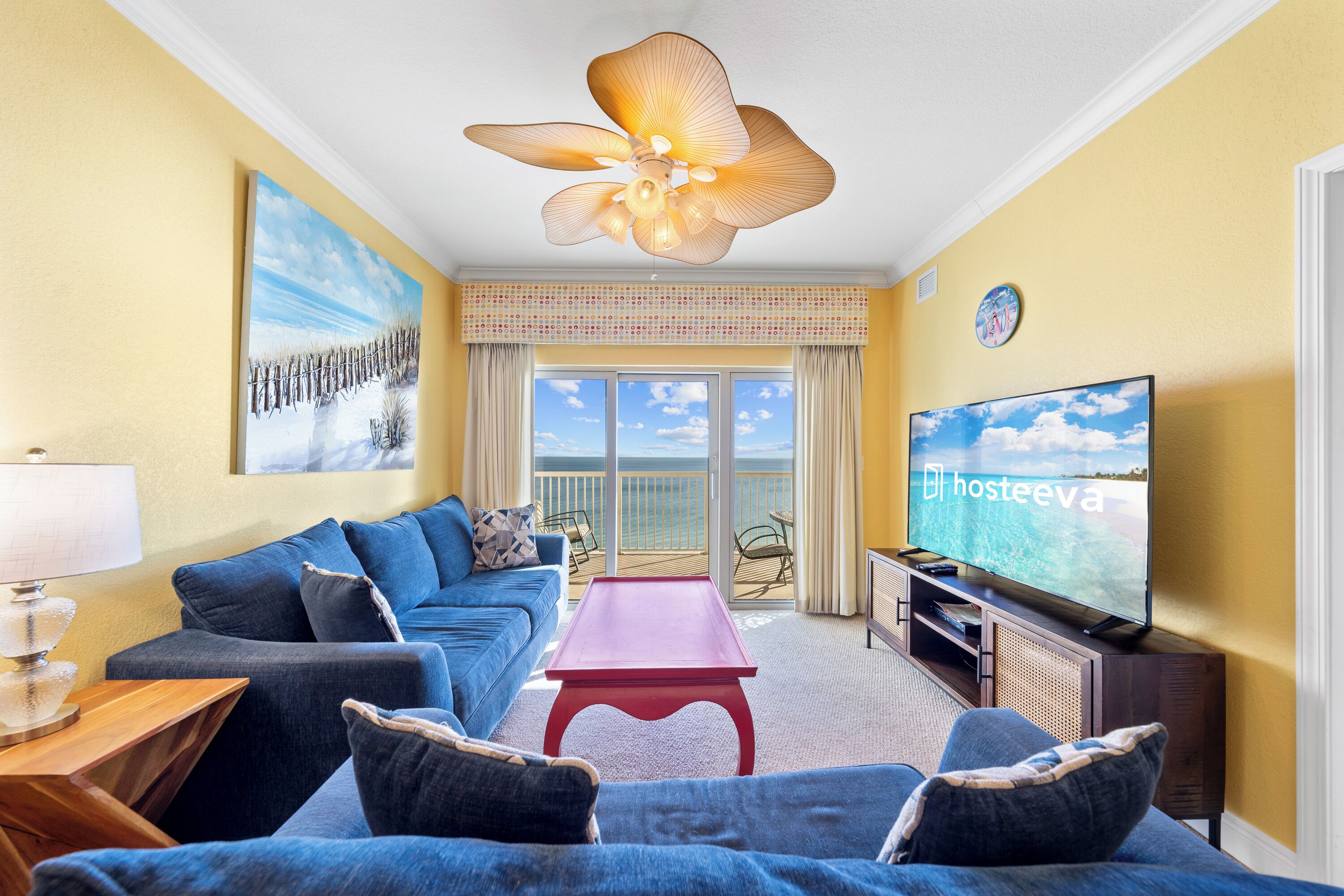 A living room with a sofa, a coffee table, a TV, and a balcony with a view.