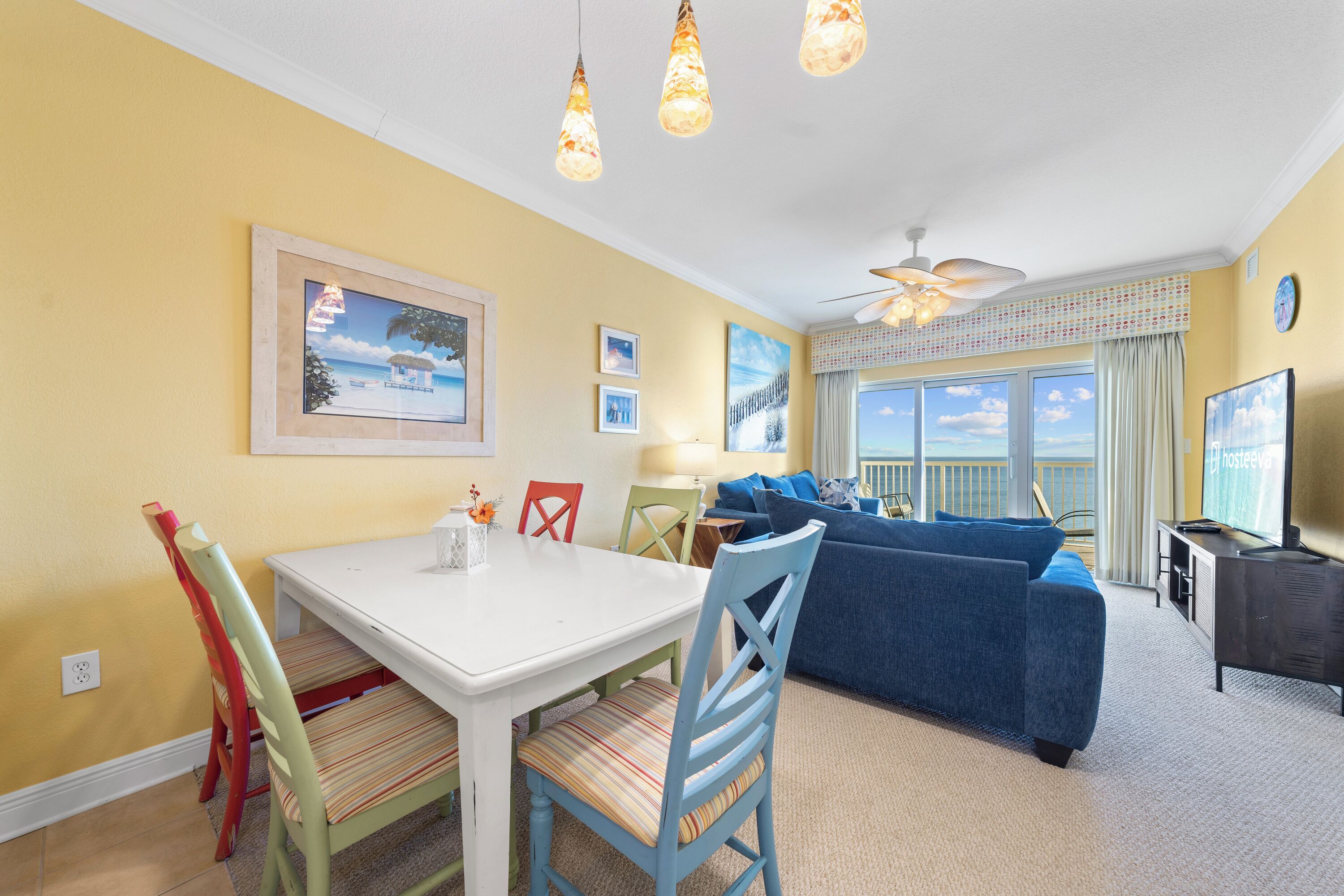 A dining area with a white table and chairs, a blue sofa, and a TV.