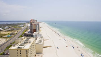 Un hôtel en bord de mer composé de plusieurs bâtiments, doté d’une plage de sable et offrant une vue dégagée sur l’océan.
