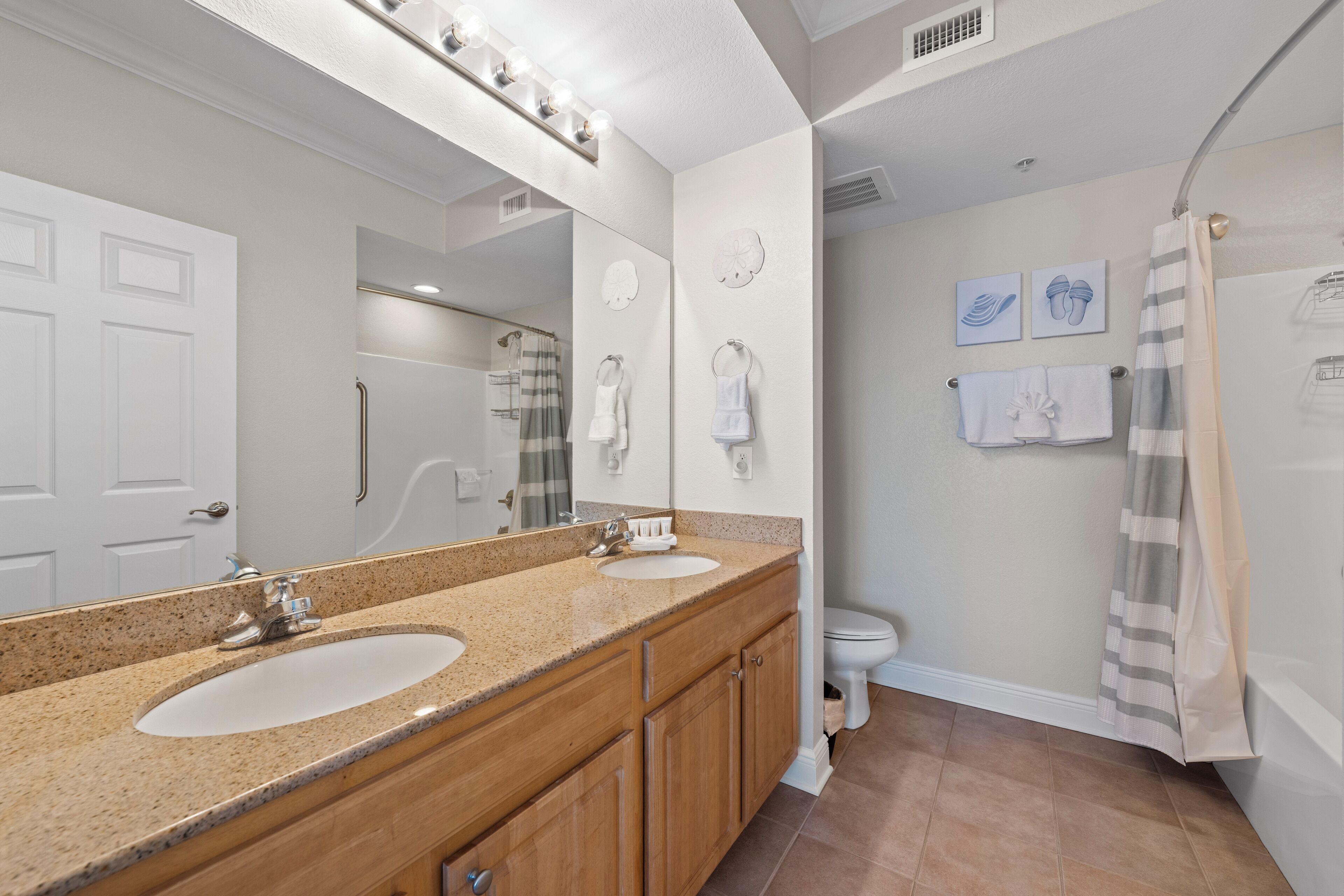 A bathroom with two sinks, a large mirror, and a shower area.