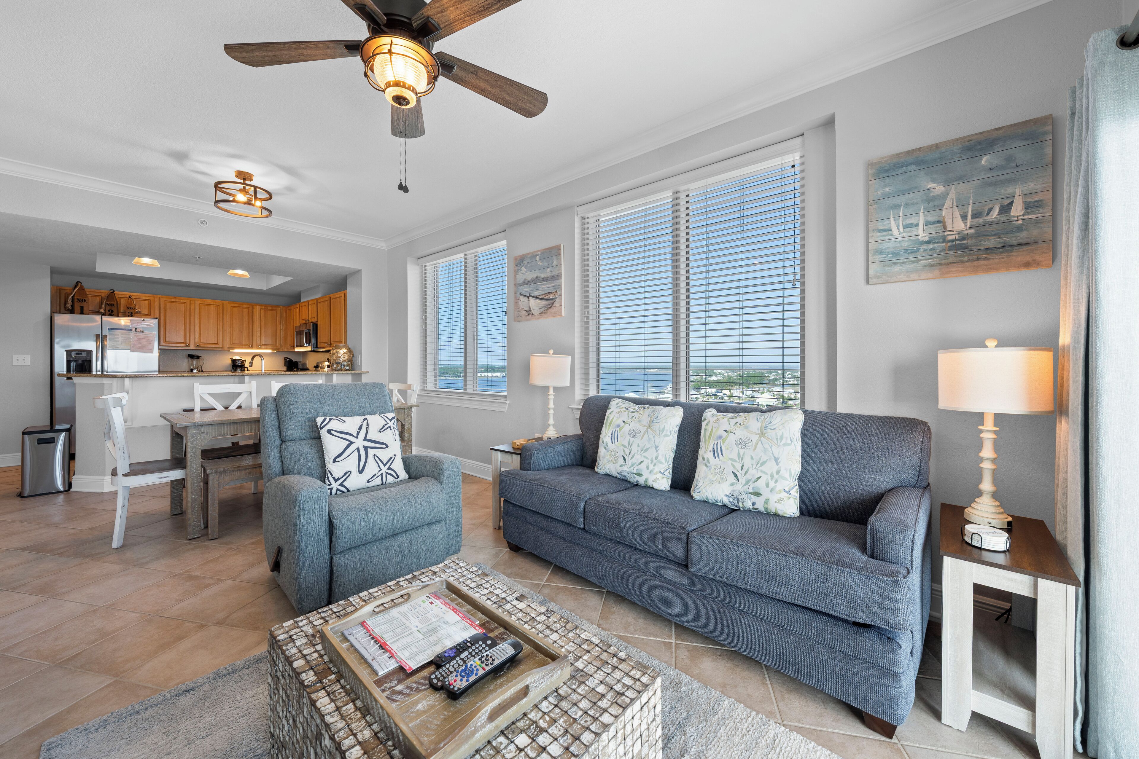A spacious living room with a grey sofa, a coffee table, and a ceiling fan.