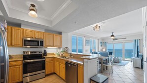A modern kitchen with stainless steel appliances, wooden cabinets, and a large island. -  Crystal Tower Condos (Gulf Shores)