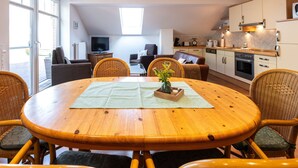 A dining area with a round wooden table, wicker chairs, and a small potted plant.