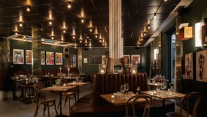 Interior de un restaurante con cabinas, mesas y obras de arte en las paredes.