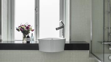A bathroom with a white sink, a mirror, and a window.