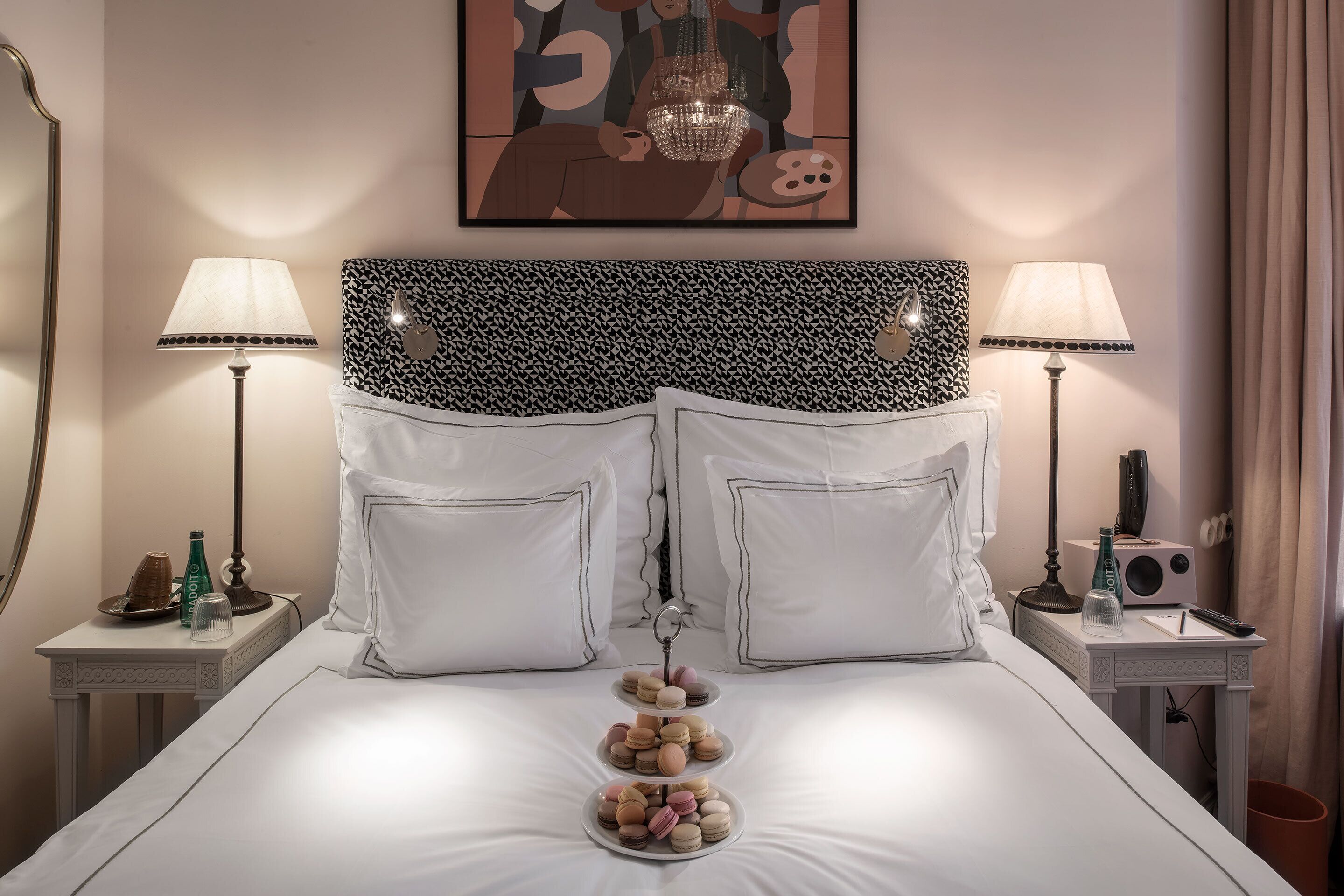 Habitación de hotel ordenada con cama, dos mesitas de noche, cabecera y un cuadro en la pared.