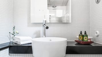Un baño con un lavabo blanco, un espejo y una encimera negra. Hay dos botellas de jabón líquido sobre la encimera.