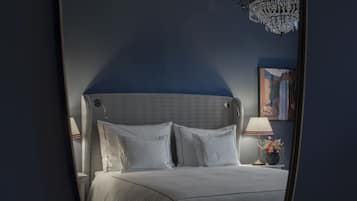 Un dormitorio con una cama grande, una araña, una mesita de noche con lámpara y un cuadro enmarcado en la pared.