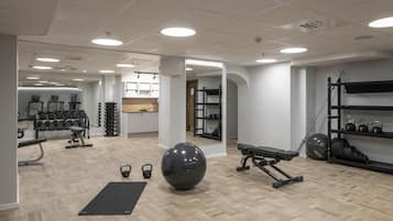Un gimnasio moderno con suelo de madera, equipamiento de ejercicio y una pelota de entrenamiento negra.