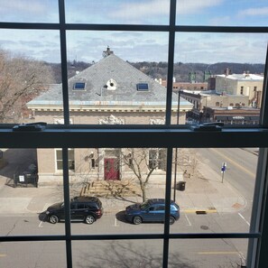 A view through a window of a parking lot with a building in the background. - Lowell Inn (Stillwater)