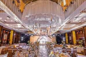 A banquet hall with round tables, a central floral arrangement, and a chandelier. - Xishan Hotel (Taiyuan)