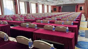 A conference room with rows of tables, each with a water bottle and a headrest.
