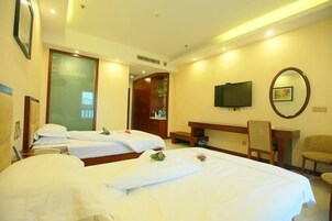 A hotel room with two beds, a desk, a chair, a television, and a mirror.