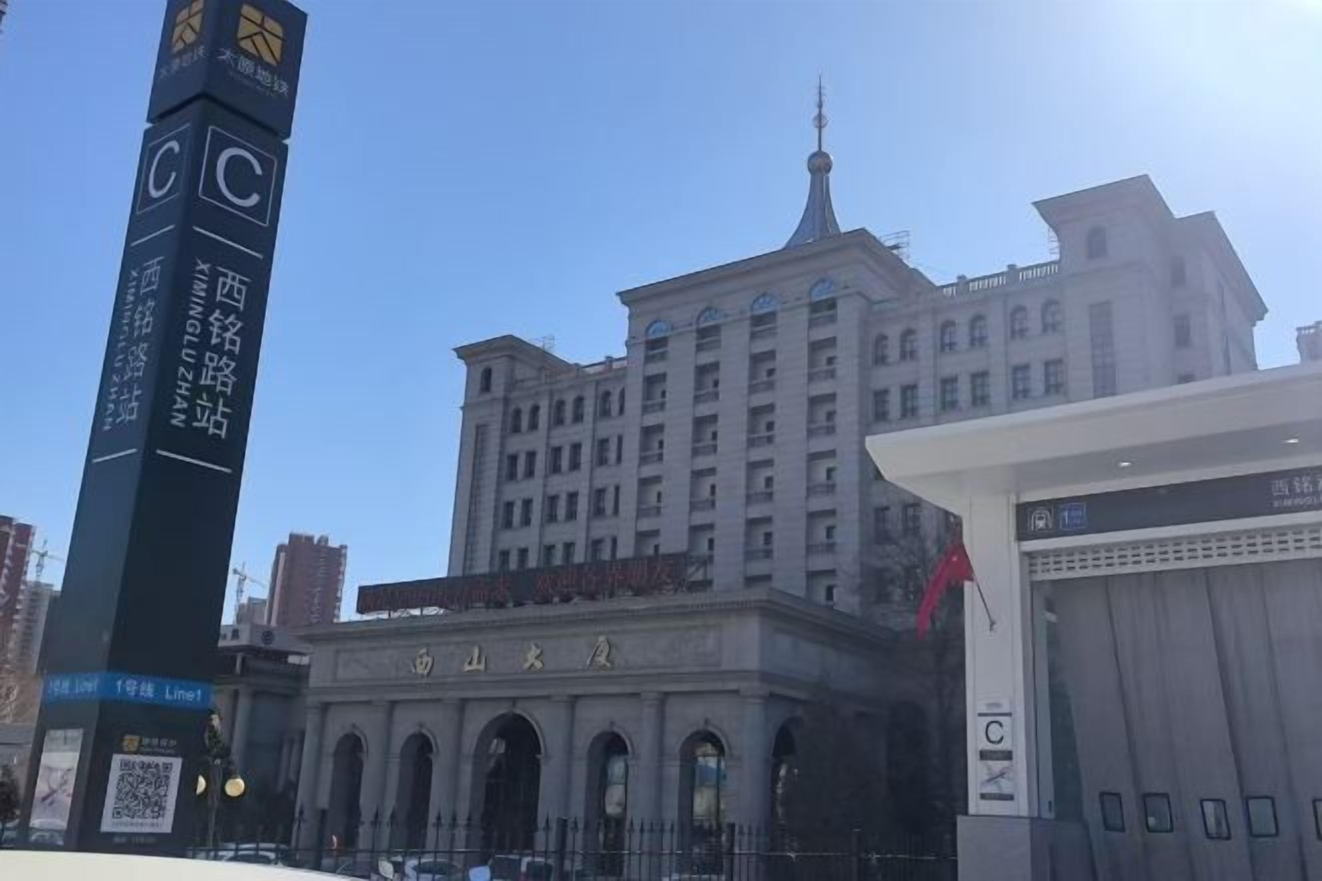 A large building with a prominent clock tower, arched entrance, and a sign with Chinese characters.