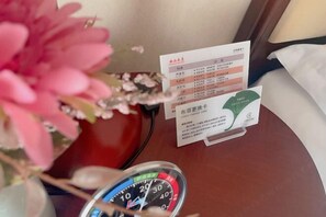 A desk with a speedometer, a card with text, and a pink flower. - Xishan Hotel (Taiyuan)