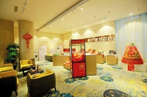 Un vestíbulo de hotel con zonas de estar, una recepción y una exhibición decorativa.