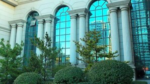 A building with large arched windows and columns, surrounded by well-maintained greenery. - Xishan Hotel (Taiyuan)