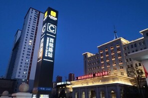 Un immeuble de grande hauteur, doté d’une enseigne lumineuse, d’un logo en forme de « C » bien visible, et d’un style architectural classique avec des fenêtres en arc de cercle.