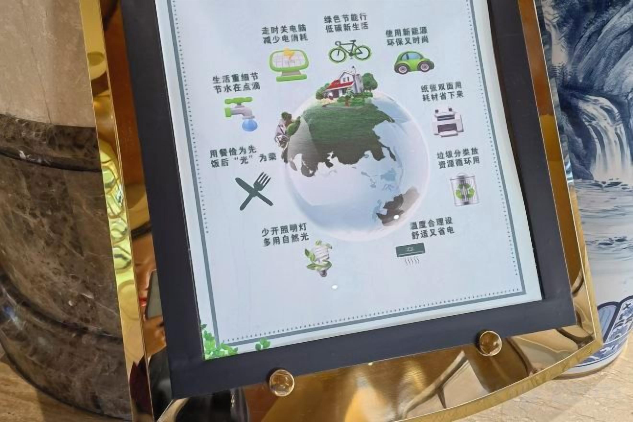 A framed informational display with a globe and various icons representing eco-friendly practices.