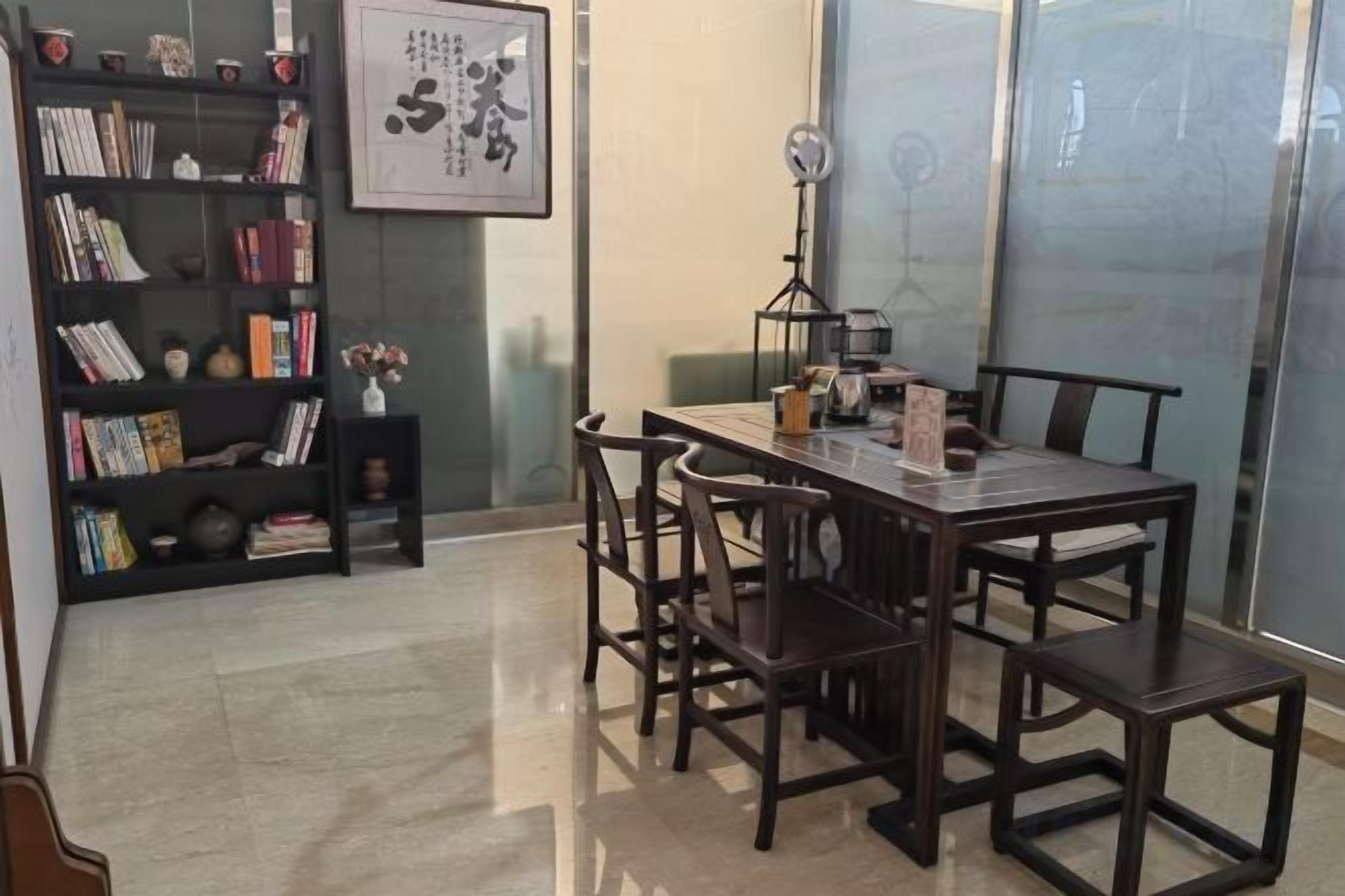 A dining area with a wooden table and chairs, a bookshelf with books, and a framed picture on the wall.