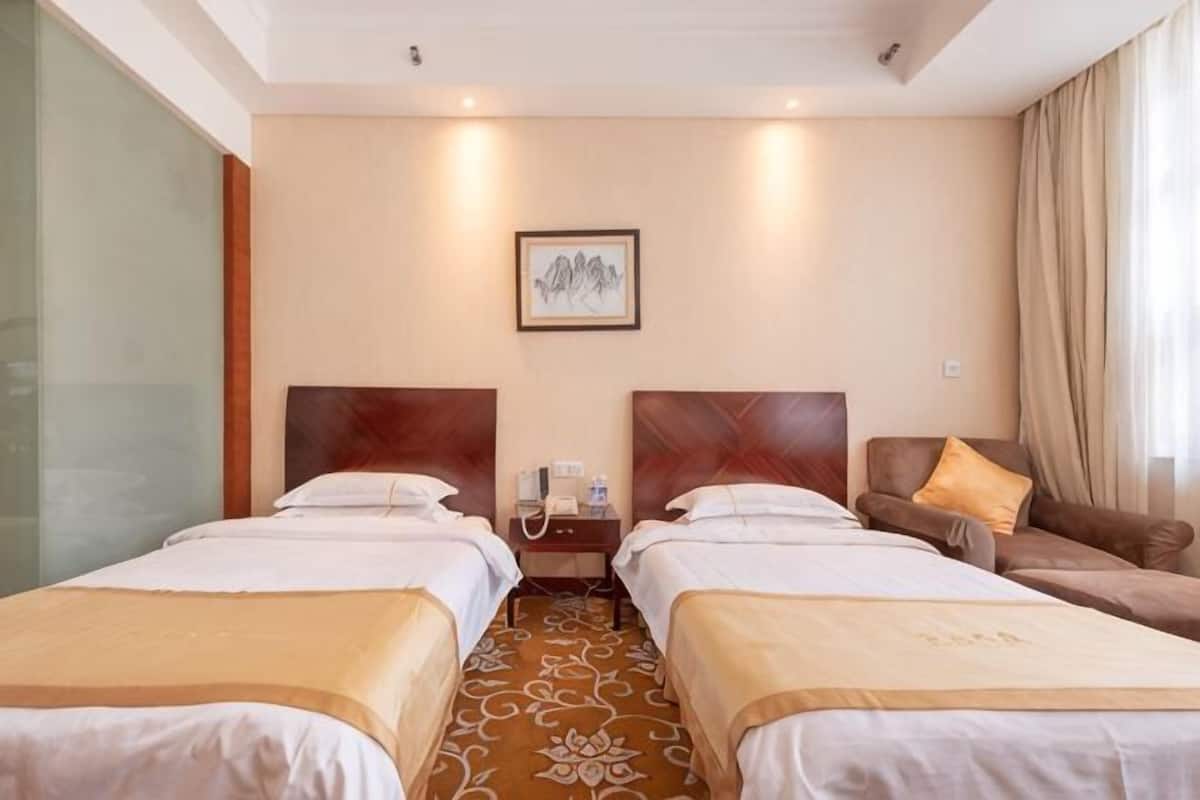 Habitació d'hotel amb dos llits, un sofà, un telèfon i un quadre al mur.