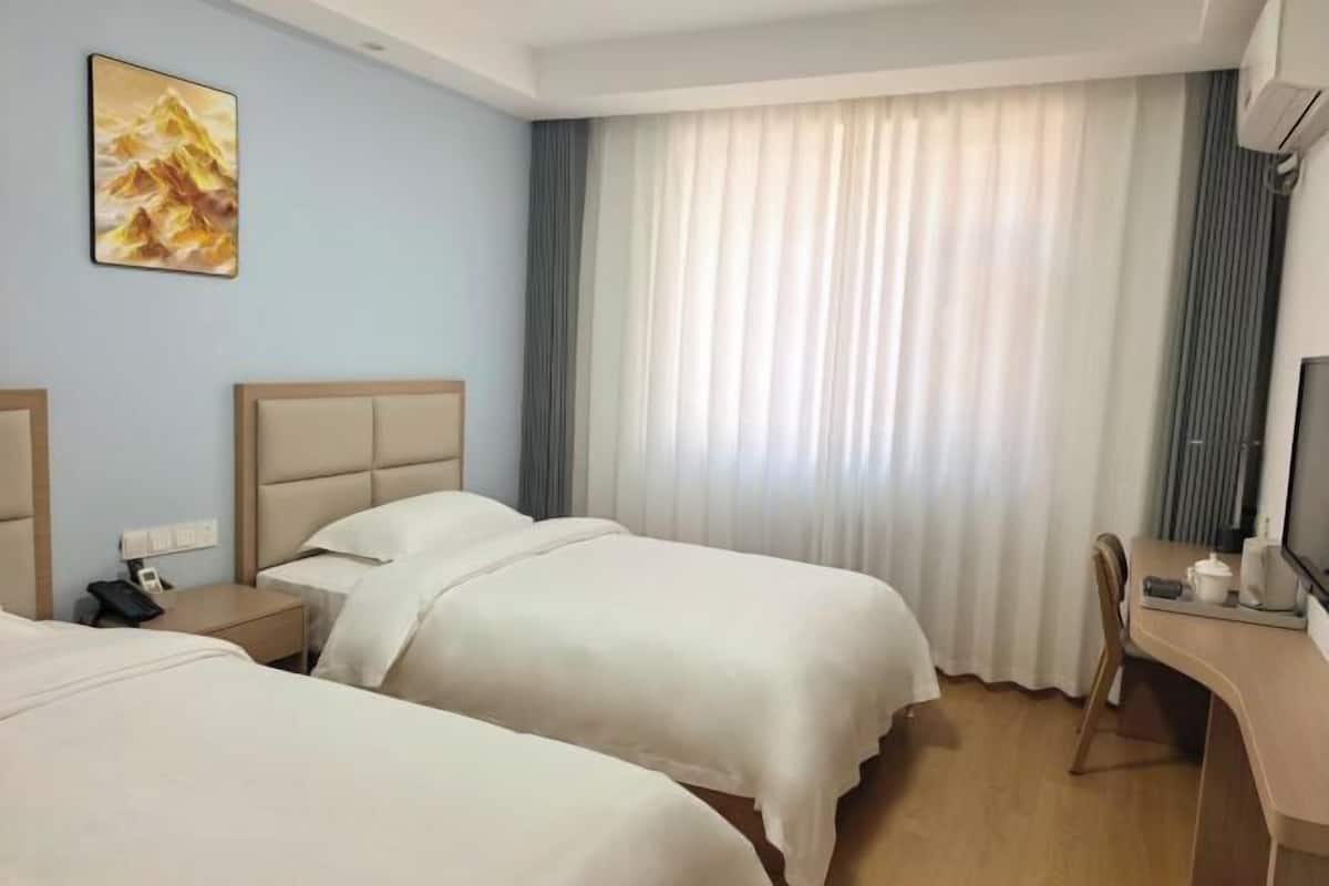 Habitació d'hotel amb dos llits, escriptori, cadira, televisió i un quadre a la paret.