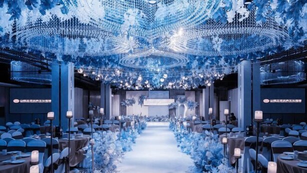 A banquet hall with a central aisle, tables on either side, and a ceiling with intricate light fixtures. - Xishan Hotel (Taiyuan)