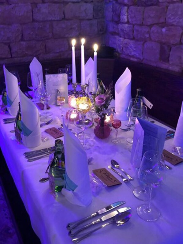 Une table dressée pour un dîner formel, avec des bougies, de la verrerie et un centre de table.