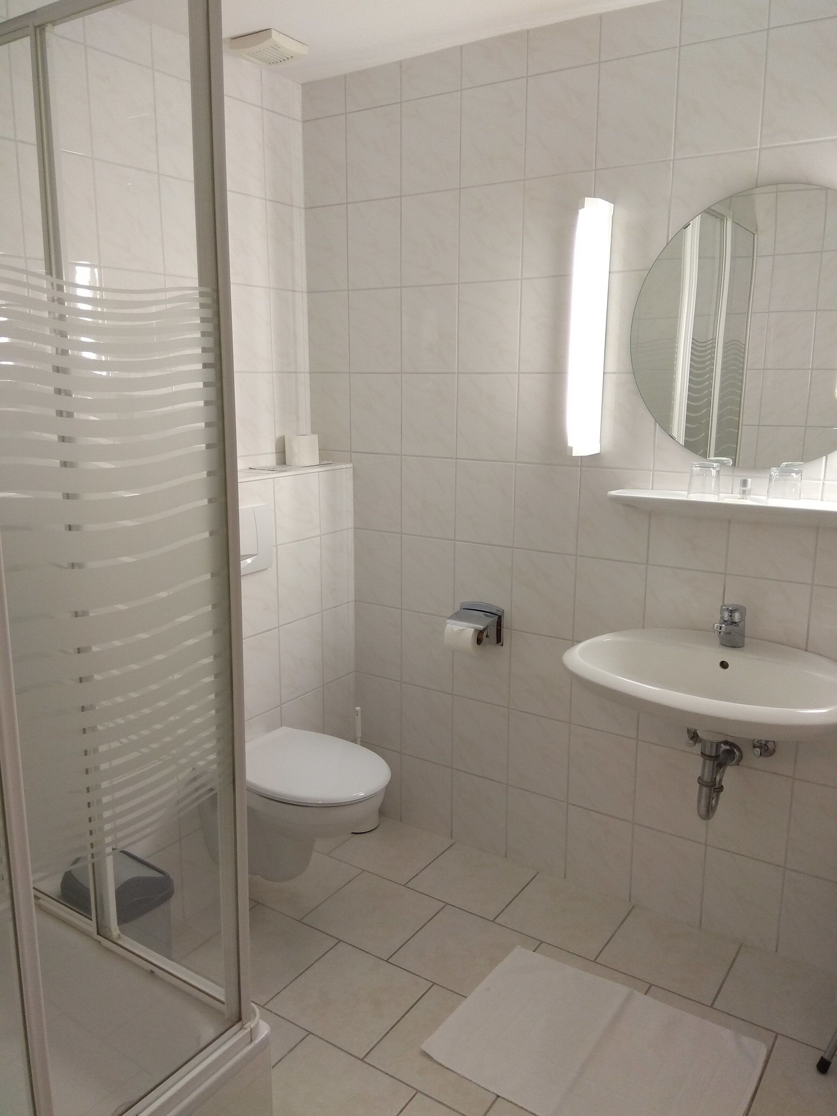 A modern bathroom with a toilet, sink, and mirror.