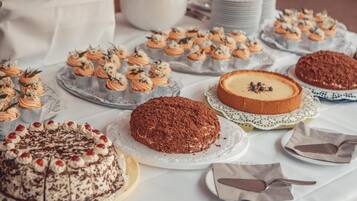 Una mesa con diversos postres, como cupcakes, pastel de chocolate y pastel de queso.