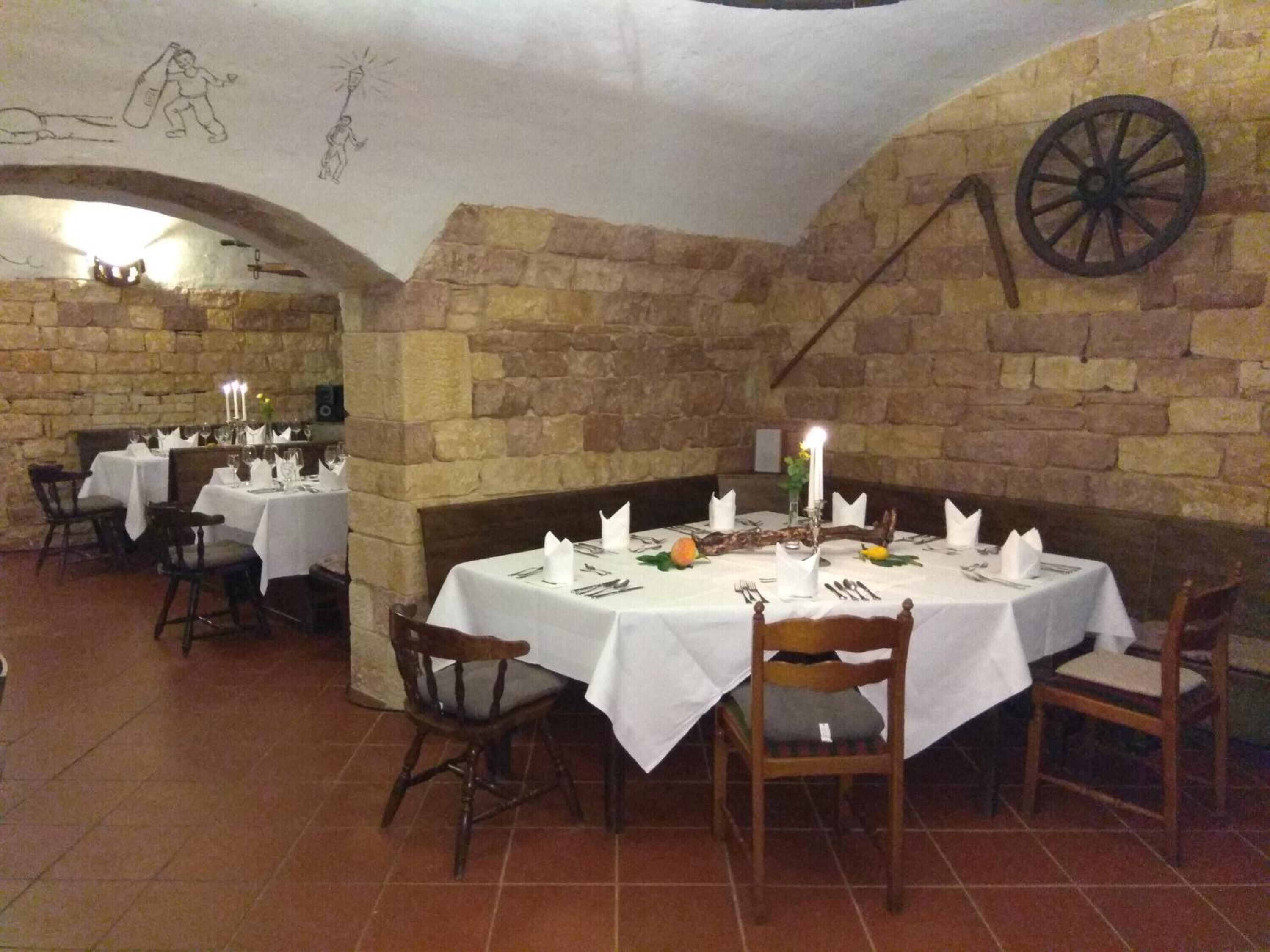 Un restaurante con paredes de piedra, manteles blancos y mesas iluminadas por velas.
