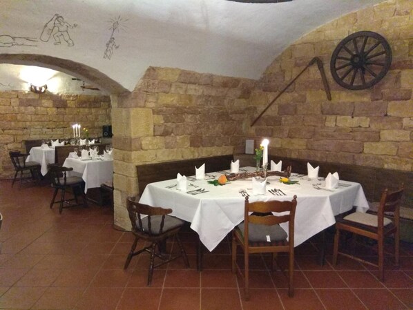A restaurant with stone walls, white tablecloths, and candle-lit tables. - Hotel-Restaurant Winzergarten (Grosskarlbach)