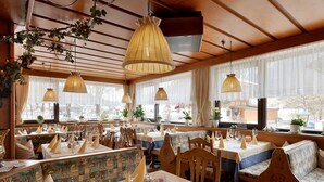 A restaurant with wooden booths, tables with white tablecloths, and hanging lamps. - Quadruple room with bath, WC - the Christophorus (Soell)