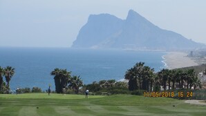 En golfbana med utsikt över havet och ett berg i bakgrunden.