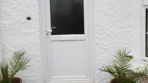 A white door with a small window above it, flanked by two potted plants. - Oxford City Guest House (Oxford)