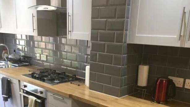 A modern kitchen with a gas stove, oven, and white cabinets. - Oxford City Guest House (Oxford)