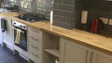 A modern kitchen with a gas stove, oven, and white cabinets.