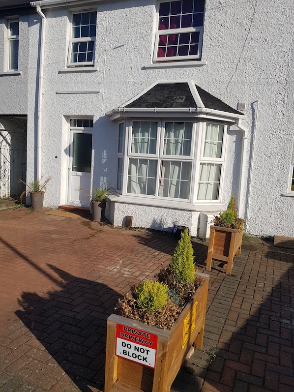 A white building with a bay window, a door, and a sign indicating a private driveway.