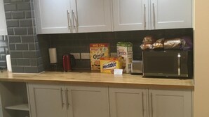 A kitchen with white cabinets, a microwave, and cereal boxes on the counter. - Oxford City Guest House (Oxford)