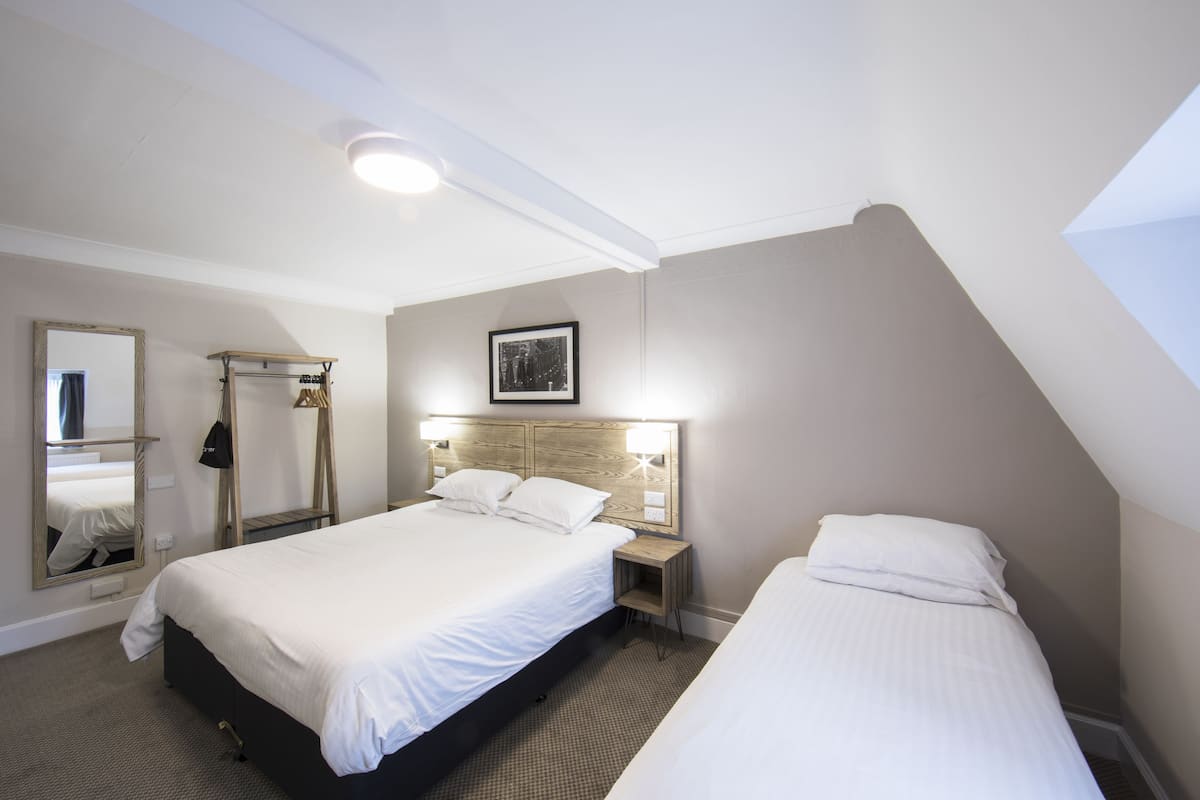 A hotel room with a large bed, a bedside table, a mirror, and a picture on the wall.