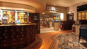 Un hall d’hôtel comprenant un bar, un sol à motifs et un écran de télévision.