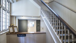Un comptoir d’accueil avec une pancarte, un escalier et une porte donnant sur une pièce.